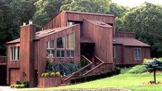 a large wooden house sitting in the middle of a lush green field next to trees