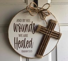 a wooden cross hanging from the side of a door with a message on it that says and by his words we are healed