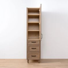 a tall wooden cabinet sitting on top of a hard wood floor next to a white wall