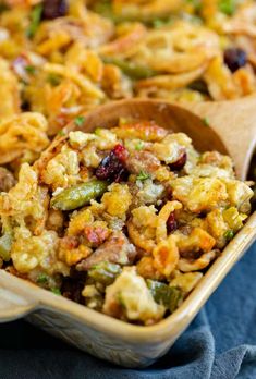 a casserole dish full of stuffing and vegetables with wooden spoons in it