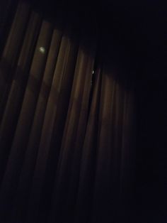 a dark room with curtains and a clock on the wall