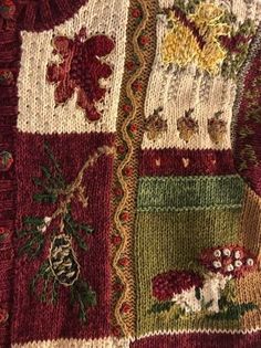 a close up of a knitted sweater with flowers and leaves on the side,