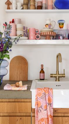 the kitchen sink is surrounded by colorful dishes and vases on shelving above it