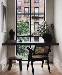 a room with a desk, chair and potted plant in front of a window