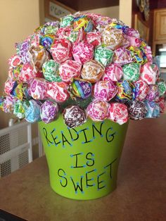 a green bucket filled with candy sitting on top of a table next to a wall