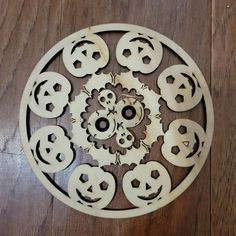 a wooden clock with many faces carved into it's face on a wood floor