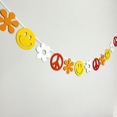 a peace sign, flowers and smiley faces on a white string with paper cutouts