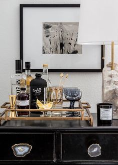 a bar cart with liquor bottles and glasses on it in front of a framed photograph