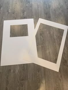 two pieces of white paper sitting on top of a wooden floor