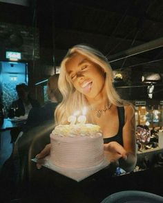 a woman holding a birthday cake with lit candles on it in front of her face