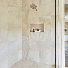 a bathroom with white marble walls and flooring next to a walk - in shower