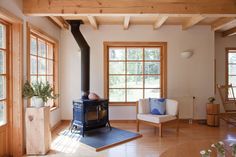 a living room filled with furniture and wooden floors next to two large windows covered in wood planks