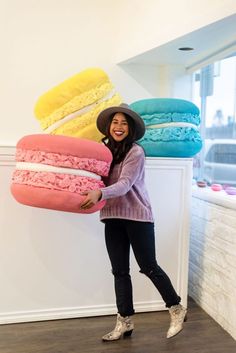 a woman in a hat is holding up some doughnuts that are stacked on top of each other