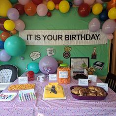 a birthday party with balloons and food on the table