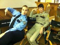 two female police officers sitting next to each other in chairs and posing for the camera