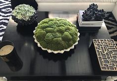 a black table topped with a green cake next to a candle and other decor items