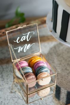 a box filled with macaroons sitting on top of a table next to a cake