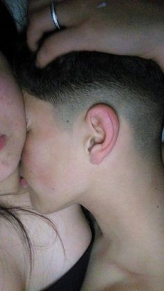 a young man and woman laying next to each other with their heads close together in bed