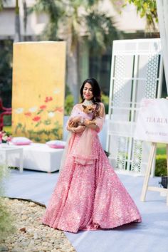 a woman in a pink dress is holding a small dog and posing for the camera