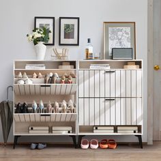 a white cabinet with shoes on the bottom shelf next to it and framed pictures above