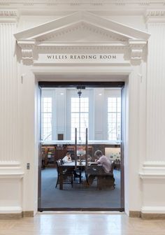 a person sitting at a table in the middle of a room with columns and windows