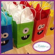 colorful paper bags with faces on them are sitting on a table in front of a purple sign