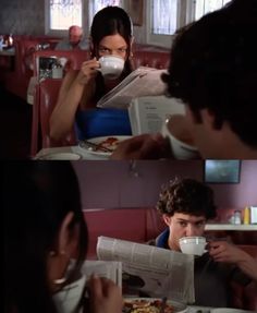 two people sitting at a table in a restaurant, one reading a newspaper and the other drinking coffee