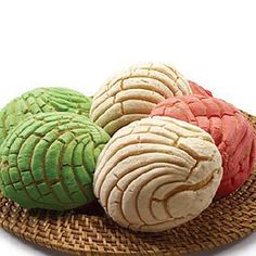 three different colored cookies sitting on top of a wicker plate