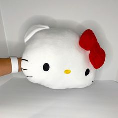 a hello kitty stuffed animal being held up by someone's hand on a white surface