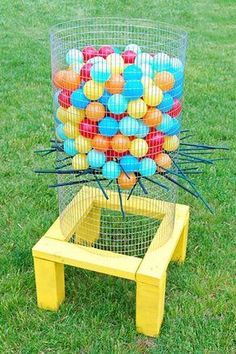 a bunch of balls that are in a cage on the grass near a table and chair