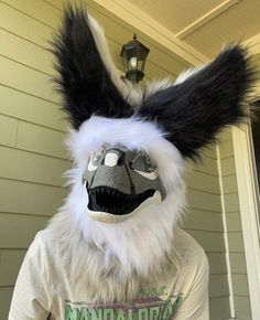 a person wearing a furry animal mask and t - shirt in front of a house