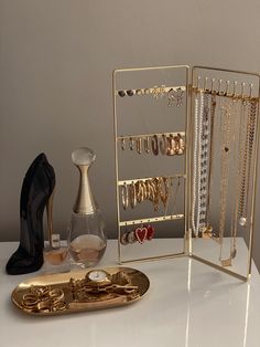 gold jewelry and shoes are sitting on a white table next to an open case with several necklaces in it