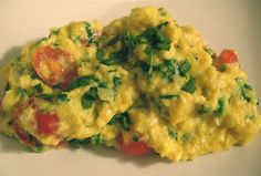 scrambled eggs with tomatoes and chives on a white plate