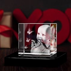 a small glass block with a baby in it's lap and butterflies on the background