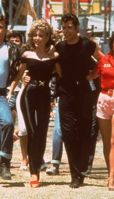 the cast of grease dancing in front of a group of people on a city street