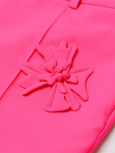 a pink pants with a flower on the side and a button at the bottom that is attached to it