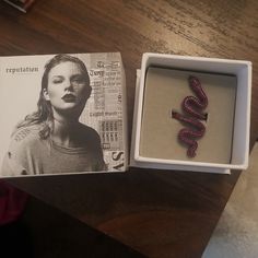 an open box with a necklace in it and a magazine on the table next to it