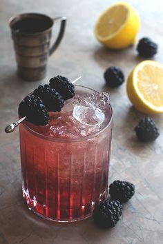 a drink with blackberries and lemons on the table