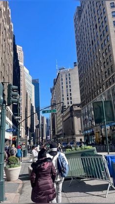 people are walking down the street near tall buildings