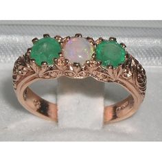 *This gorgeous trilogy ring is made from Solid 375 9ct 9K Rose Gold with Natural Semi-precious Opal and Emeralds.This ring has been completely made here in England from Solid 9ct Gold and is set with three Magnificent Gemstones. A Center Opal and Two Emeralds, equally sized measuring 4.5mm (0.18"), all individually chosen and hand set in this Substantial Ornate Antique / Victorian style setting which boasts a marvelous Foliage Scroll / Art Nouveau carving on the shoulders.PLEASE MAKE SURE YOU ST Rose Gold Heirloom Three Stone Rings, Heirloom Rose Gold Three Stone Rings, Rose Gold Three Stone Round Jewelry, Unique Three Stone Jewelry For Anniversary, Unique Three Stone Rings For Anniversary, Unique Three Stone Anniversary Rings, Victorian Three Stone Round Jewelry, Three Stone Round Jewelry For May Birthstone, May Birthstone Three Stone Round Jewelry