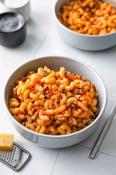 two bowls filled with macaroni and cheese on top of a white countertop