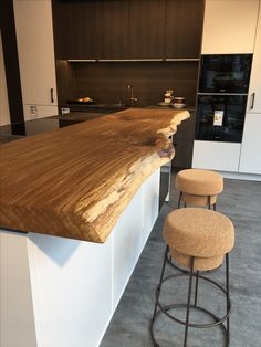 a kitchen counter with two stools in front of it and an island behind it