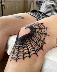 a person with a spider web tattoo on their arm and leg, sitting in bed