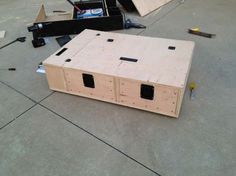 an unfinished box sitting on the ground next to other construction materials and tools that have been placed around it