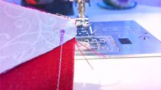 the sewing machine is working on the red piece of fabric that has been sewn