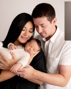 a man and woman holding a baby in their arms