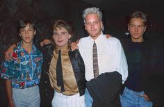 three young men standing next to each other in front of a man with white hair