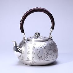 a silver tea pot with a wooden handle