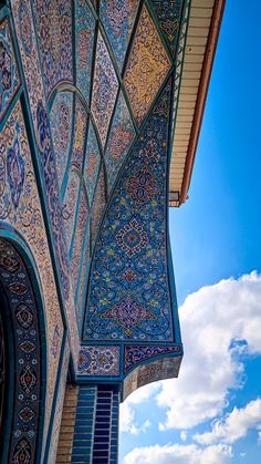 an intricately decorated building with blue sky and clouds in the backgrouds