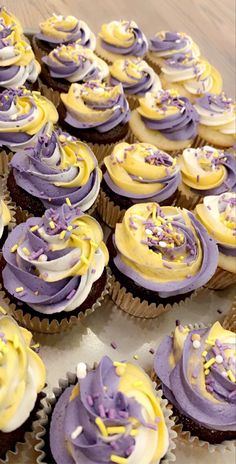 cupcakes with yellow and purple frosting are on a tray together, ready to be eaten